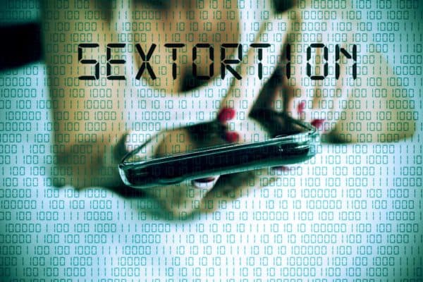 The Crime of Sexual Extortion in Vista, California 1 A digital text reading "sextortion" over a woman on her phone.