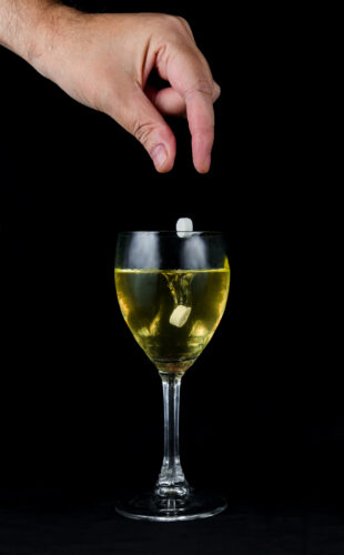Rape & Sexual Assault Defense 3 A hand dropping pills in a drink to perform a date rape