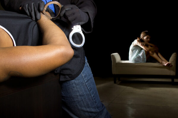 Rape & Sexual Assault Defense 2 A man is handcuffed while a potential rape victim looks depressed on the bed